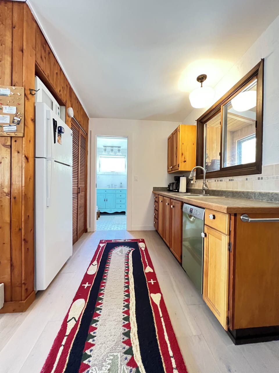 Cook with ease in this cozy, well-stocked galley kitchen featuring warm wood cabinetry, modern appliances, and a splash of personality.