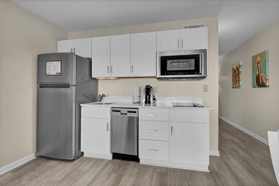 Your modern kitchenette features everything you need: stainless steel appliances, crisp white cabinets, and thoughtful touches like a coffee maker for your morning brew.