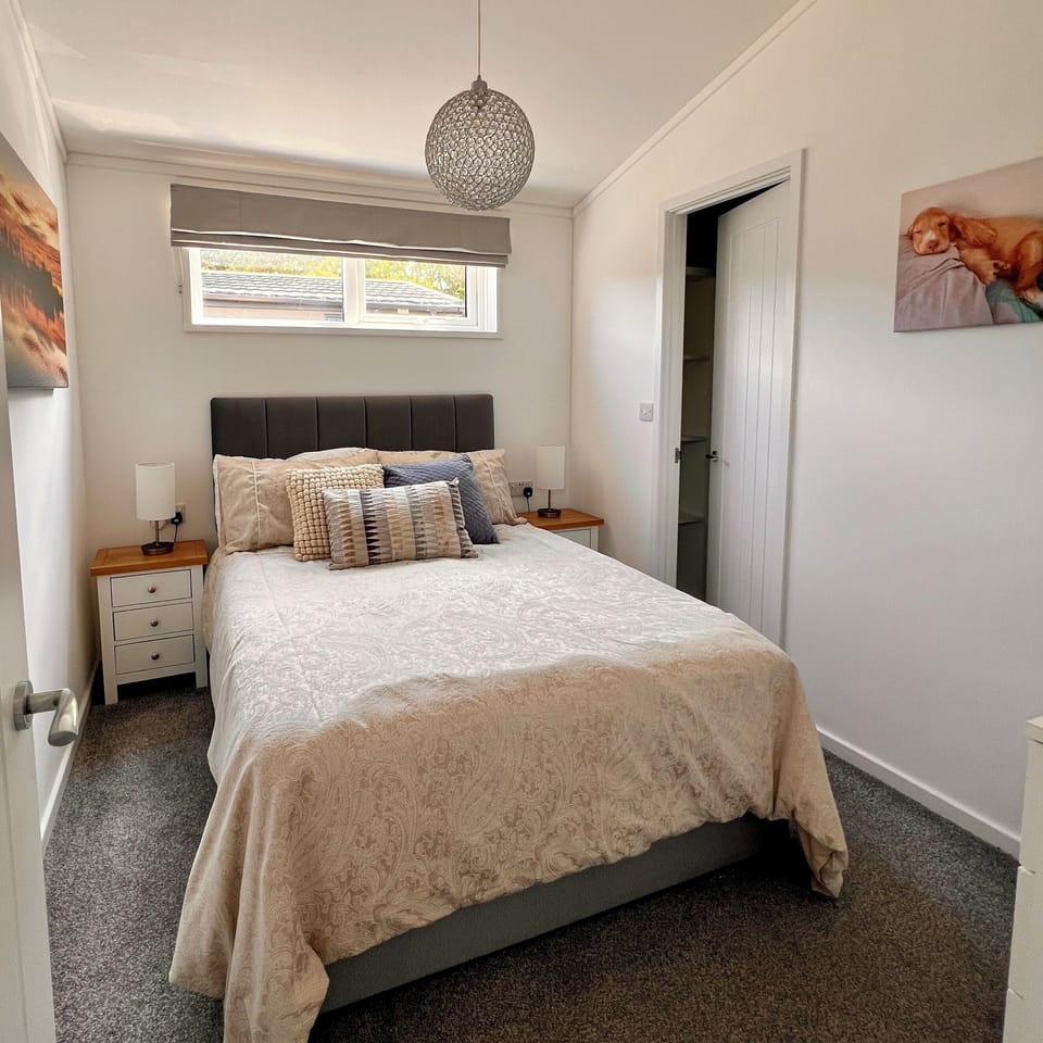 The double bedroom features a tranquil atmosphere with bedside tables and lamps on either side of the bed. A spacious walk-in wardrobe offers ample shelving and hanging space for convenient storage. 