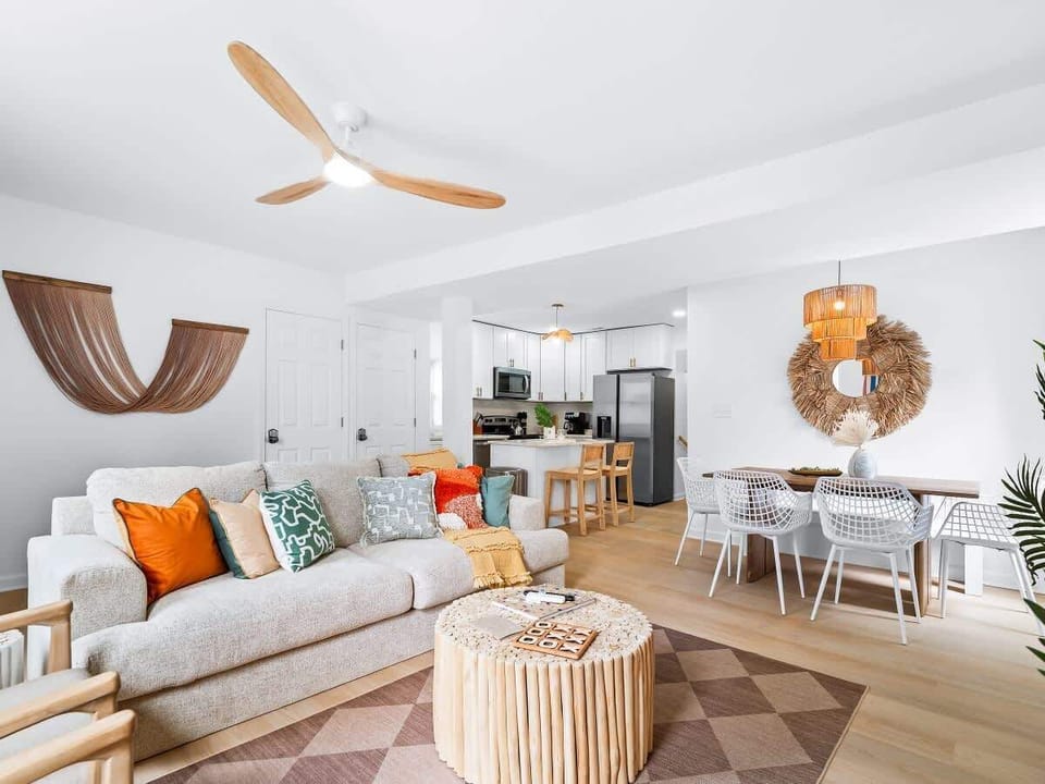 - Spacious open-concept layout connecting living room and kitchen   - Vibrant sofa with colorful pillows brightens up the cozy space   - Perfect Airbnb setup for gatherings, dining, and relaxation  