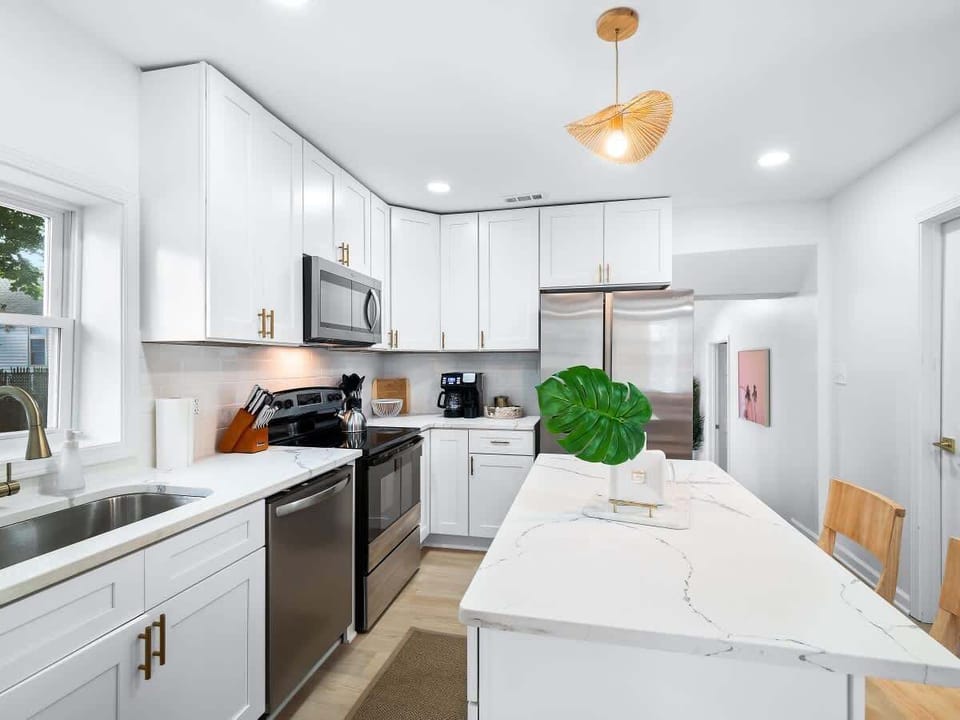 - Sleek kitchen with stainless steel appliances and bright white cabinets   - Spacious island with bar seating perfect for group dining   - Fully equipped Airbnb kitchen ideal for extended stays  