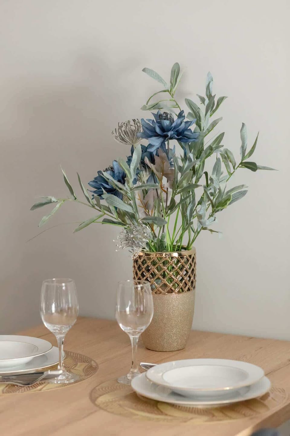 A delicate table decoration with flowers and glasses sets the scene for an elegant meal in an intimate setting.
