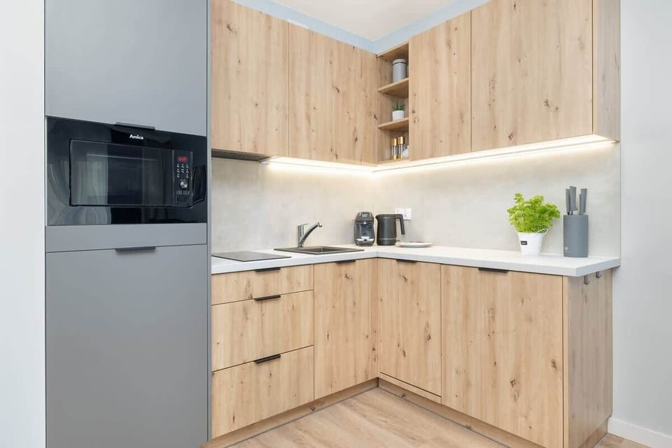 A modern kitchen with light wood and black details offers a functional space for home-style cooking.