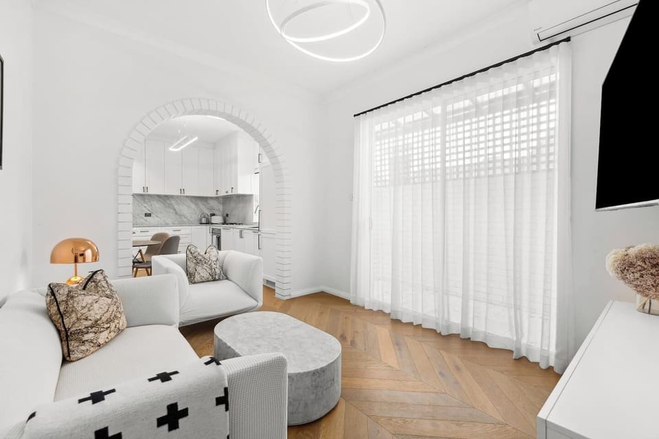 An elegantly furnished living area offers a comfy sofa and armchair to settle in with a movie or a book, with split system air conditioning and heating ensuring year-round comfort. 
