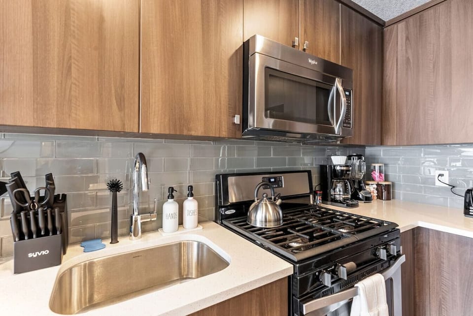 Modern kitchen corner w/ stove, microwave & sleek backsplash for easy cooking