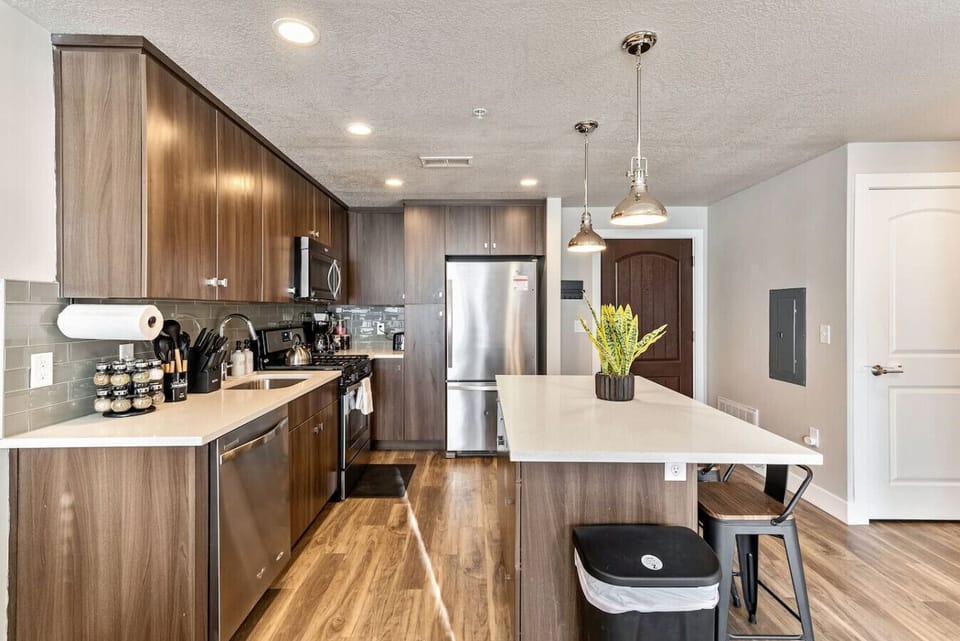 Sleek kitchen w/ large island, bar seating & warm wood cabinetry for easy meals & gathering