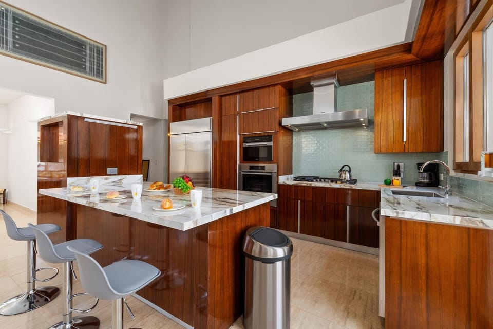 This sleek kitchen boasts a stunning array of stainless steel appliances,  expansive countertops, providing ample space for culinary creativity and effortless meal preparation, making it the perfect hub for any discerning chef.
