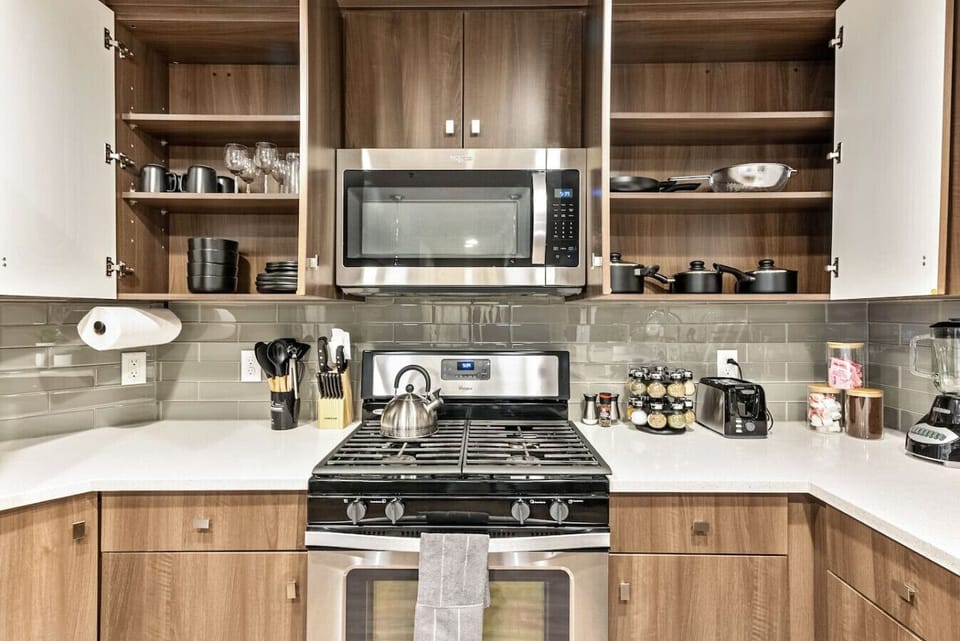 Kitchen close-up w/ gas stove, open shelving & essentials within easy reach
