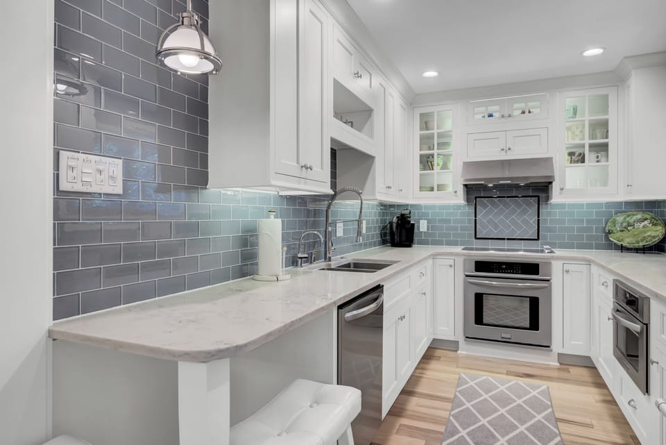 - Whip up meals or sip morning coffee in this crisp, modern kitchen with marble counters - Subway tile backsplash, pendant lighting, and stainless steel accents elevate the space - Grab a seat at the bar for breakfast, snacks, or late night chats