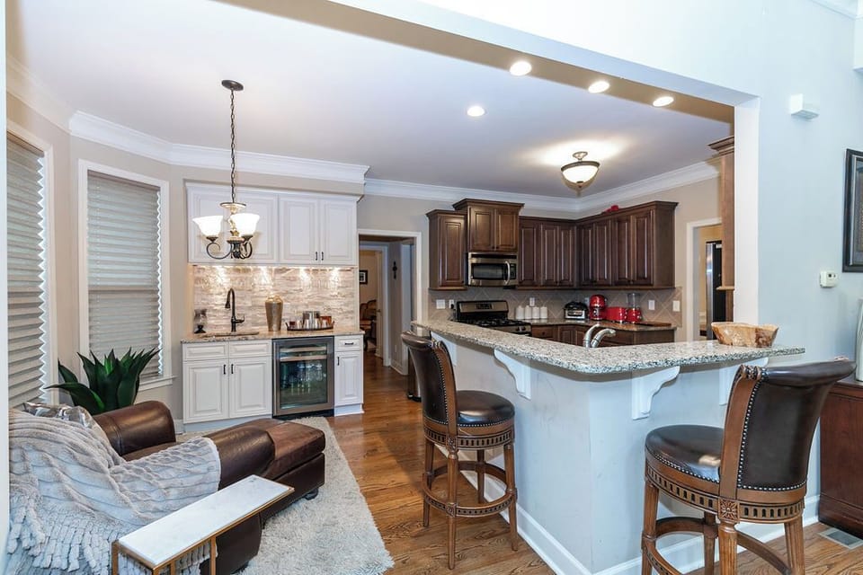 This open kitchen blends function and comfort with a wet bar to the side, a cozy lounge chair nearby, and counter seating for gathering and chatting while meals are prepared.
