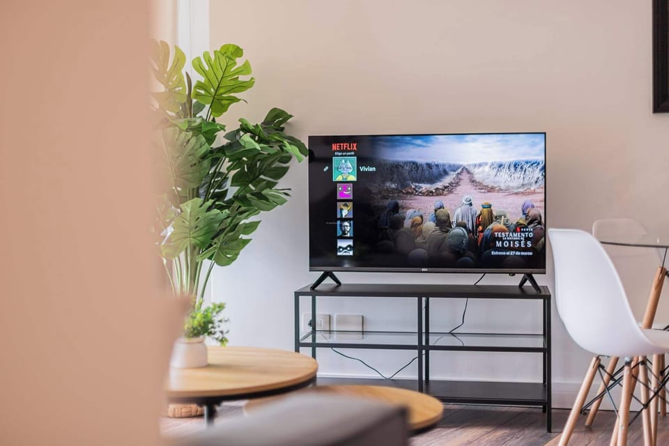 Relax in style with Netflix on a sleek TV, surrounded by modern decor and a cozy dining space.
