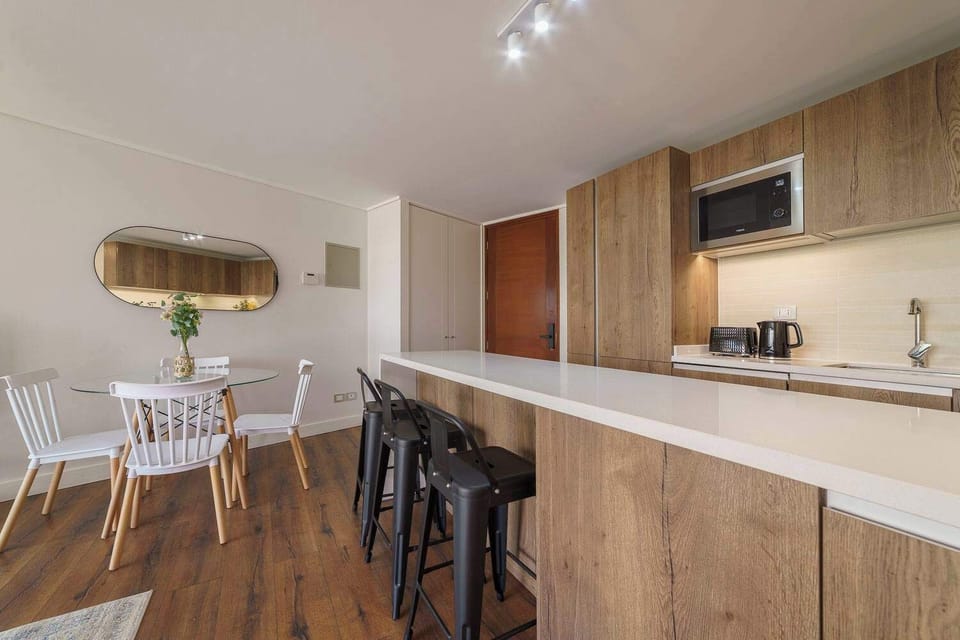 Modern kitchen with sleek wooden finishes and a cozy dining area, perfect for enjoying meals and gatherings.