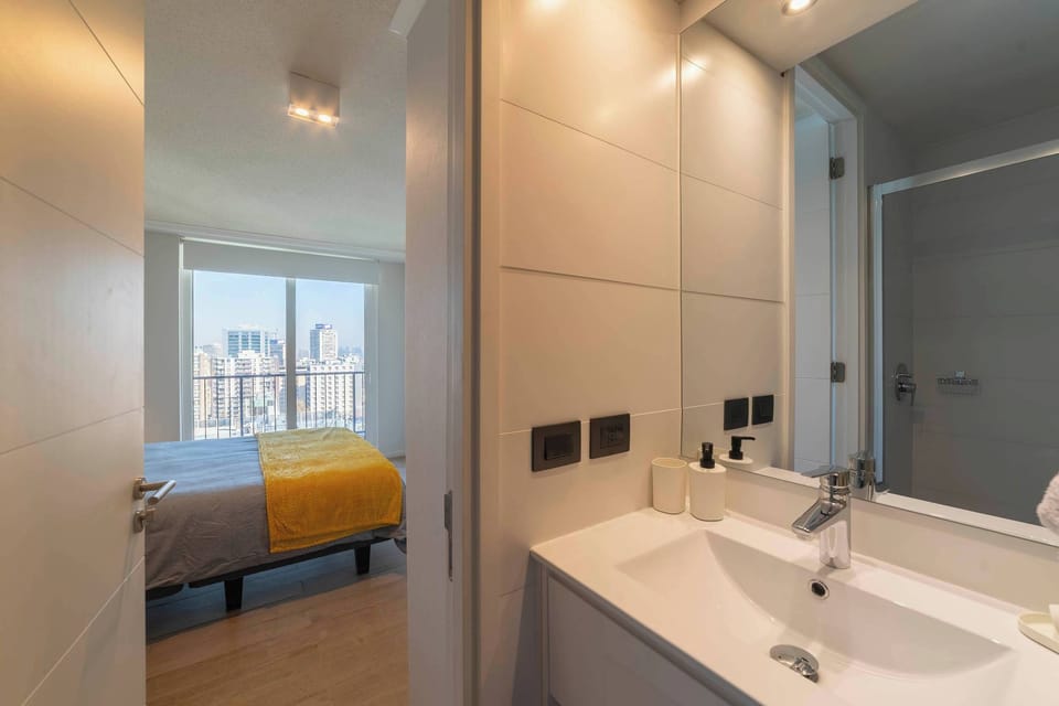 Bright and modern bathroom with city views from the adjoining bedroom, perfect for a relaxing stay.