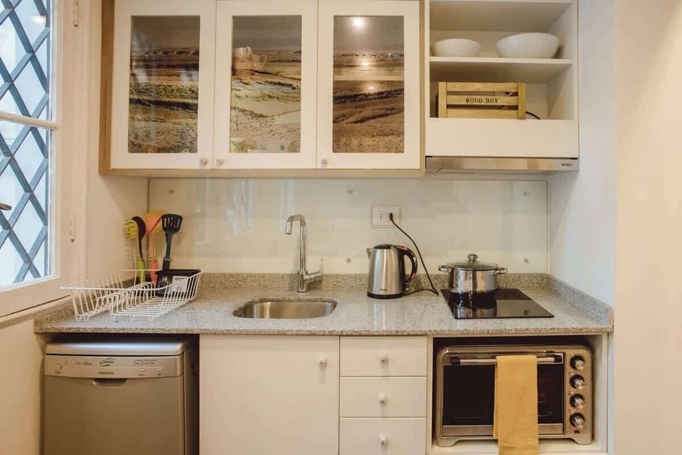 Charming compact kitchen with modern appliances and scenic cabinet art, perfect for cozy culinary adventures.