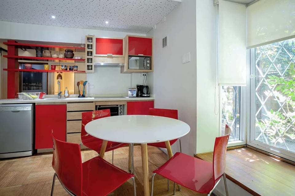 Bright and modern kitchen with vibrant red accents and a cozy dining area, perfect for enjoying meals with a view.