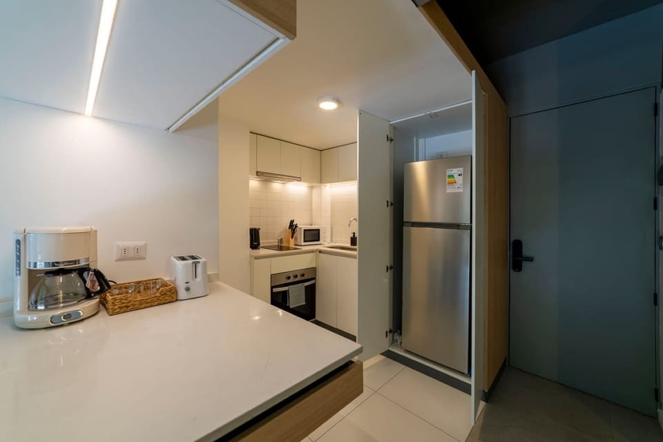 Modern compact kitchen with all essentials for a comfortable stay, featuring sleek appliances and ample counter space.