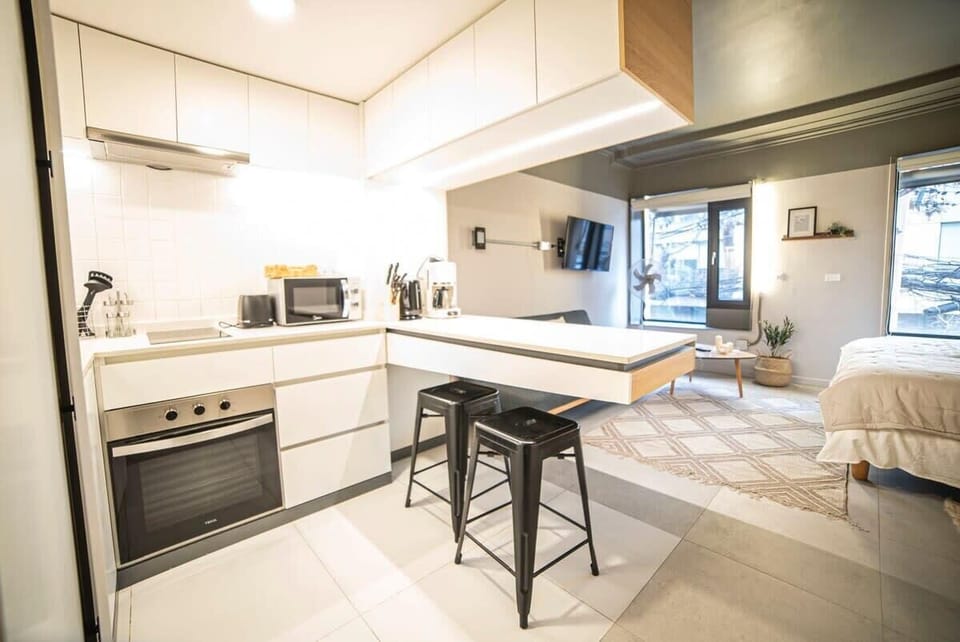 Chic studio with modern kitchen, cozy sleeping area, and abundant natural light—perfect for a stylish city retreat.
