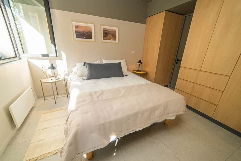 Relax in this bright and cozy bedroom with natural light and stylish decor, perfect for a restful stay.