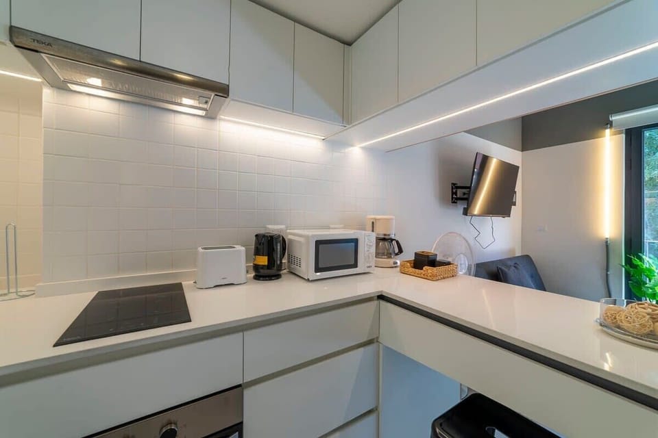 Sleek and modern kitchen with all essentials for a comfortable stay. Enjoy cooking with top appliances and unwind with a wall-mounted TV in the cozy seating area.