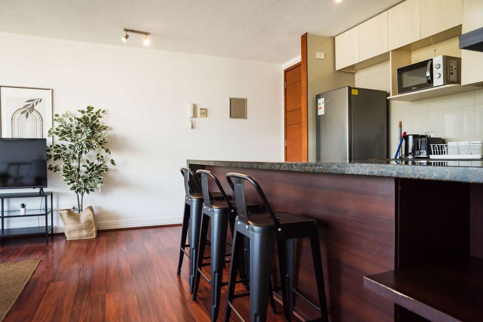 Stylish kitchen with bar seating, modern appliances, and a cozy TV area perfect for relaxing after a day exploring the city.