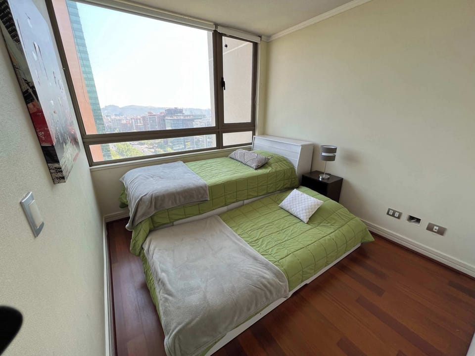 Cozy bedroom with twin beds and stunning city views, perfect for a restful stay.
