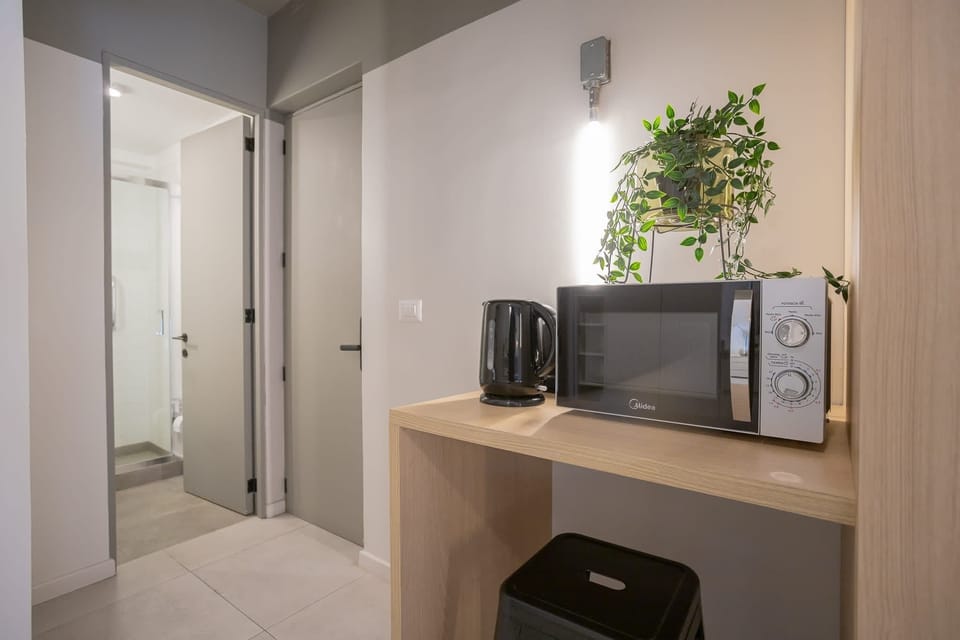 Cozy kitchenette with modern appliances and a touch of greenery, perfect for quick meals and snacks.