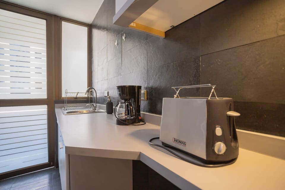 Enjoy your morning coffee in this sleek, modern kitchen with ample natural light and essential appliances.