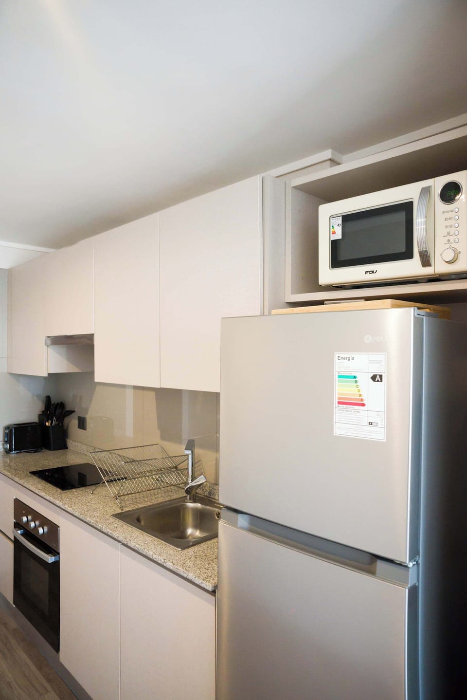 Modern studio kitchen with sleek appliances and granite countertops, perfect for cozy meals in Chile.