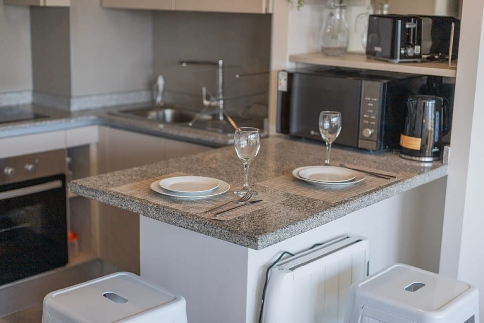 Modern kitchen with sleek appliances and cozy dining space for two.
