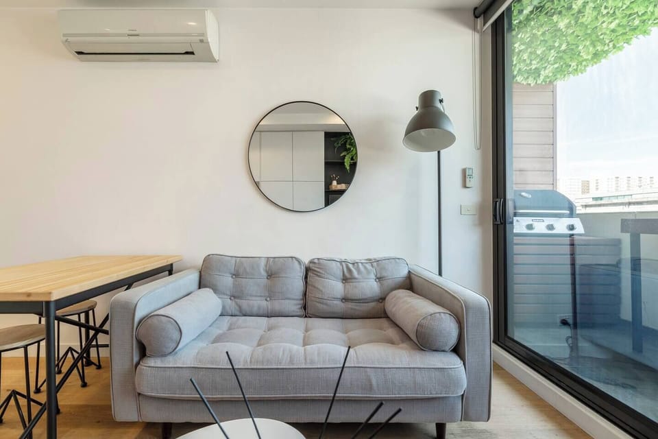 The living area features a sofa and TV, with glass doors opening out onto the balcony.
