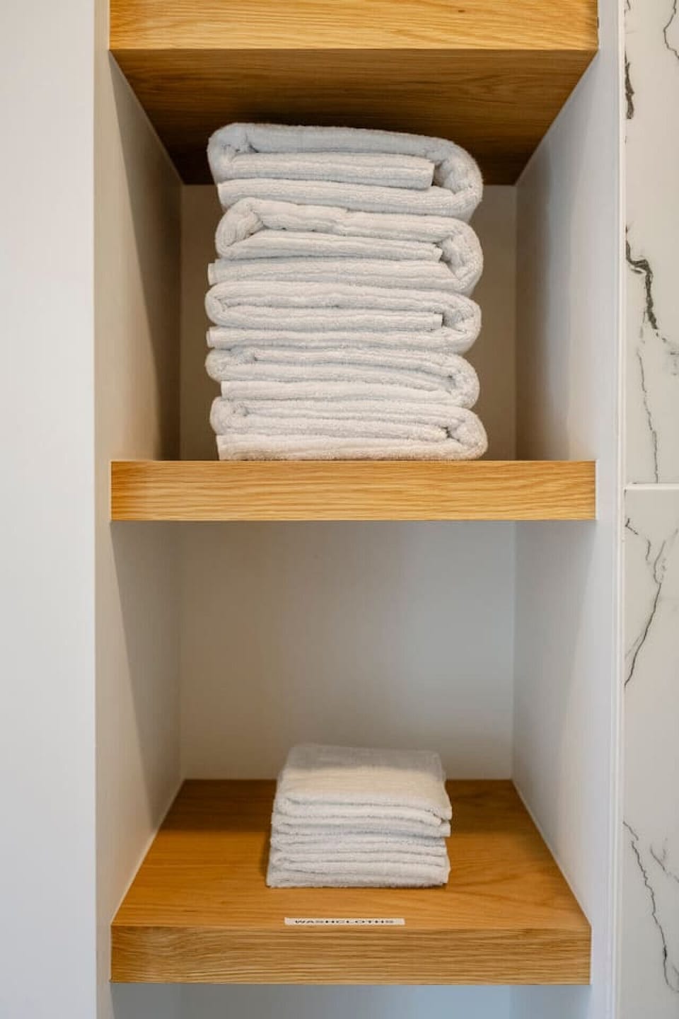 Fresh folded towels neatly stacked on open wood shelving