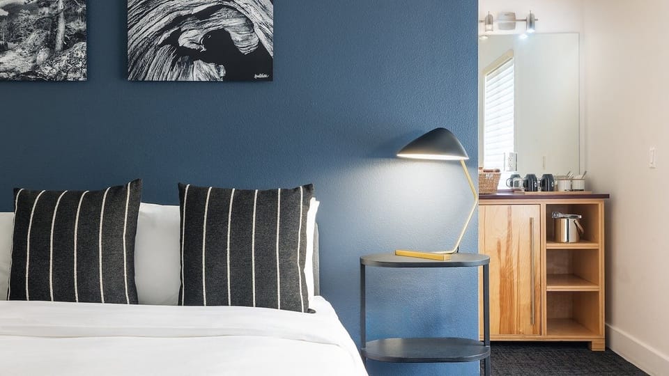 Linger with warm lamplight and thoughtful details by the bed.