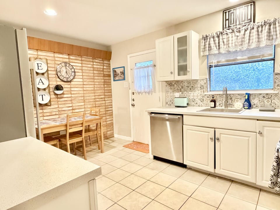 Kitchen dining nook with light wood table and chairs, brick accent wall, and patterned tile backsplash.