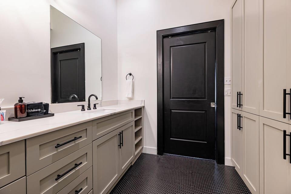 The primary bathroom offers sleek finishes, a soaking tub with Smart TV, walk-in shower, and plush towels. Spacious and private, it adds a luxurious touch to your suite—perfect for unwinding after a day in Downtown New Orleans.