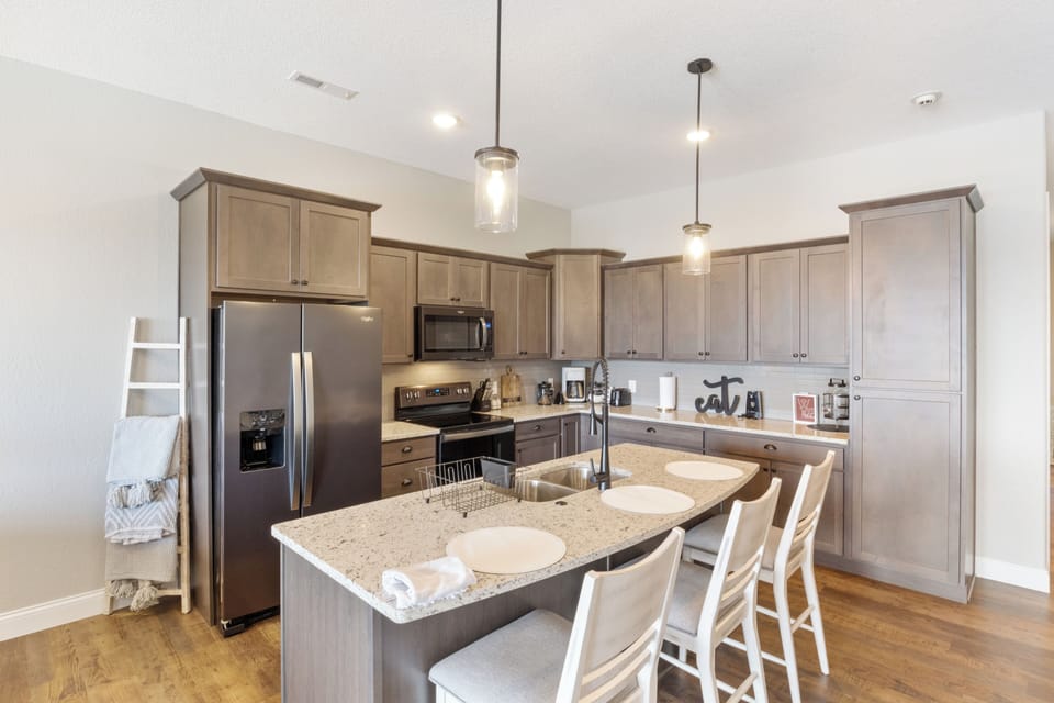 Beautiful modern kitchen with granite countertops, stainless steel appliances, and a large island with seating for four.