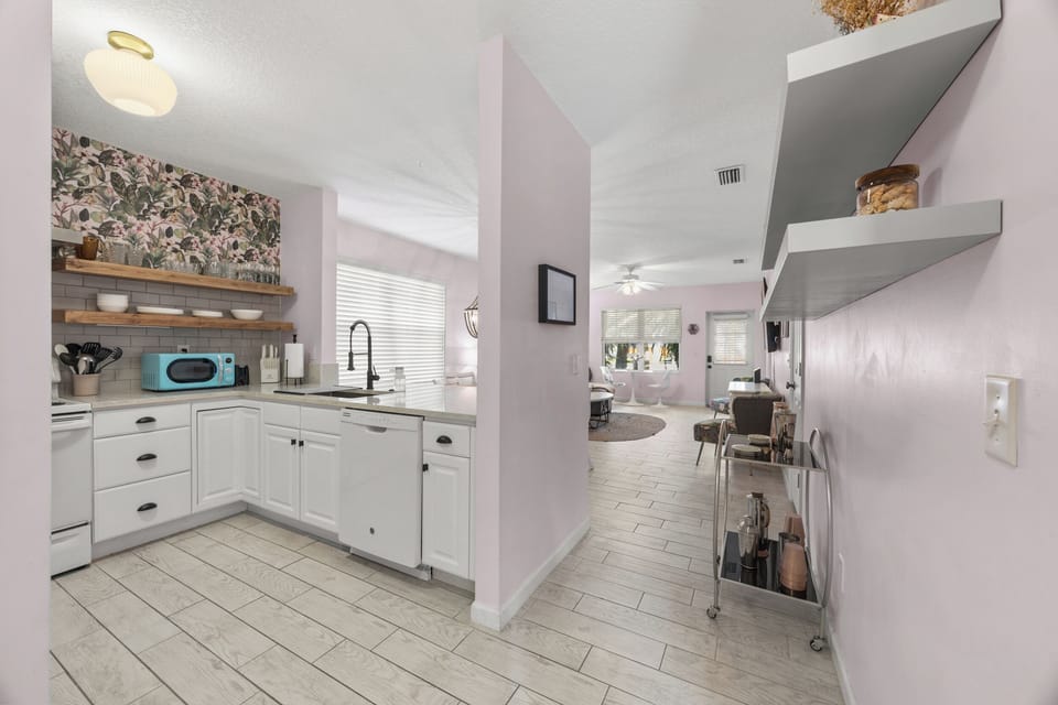 Open‑concept kitchen and living space with modern appliances, floating shelves, and a bright coastal vibe.