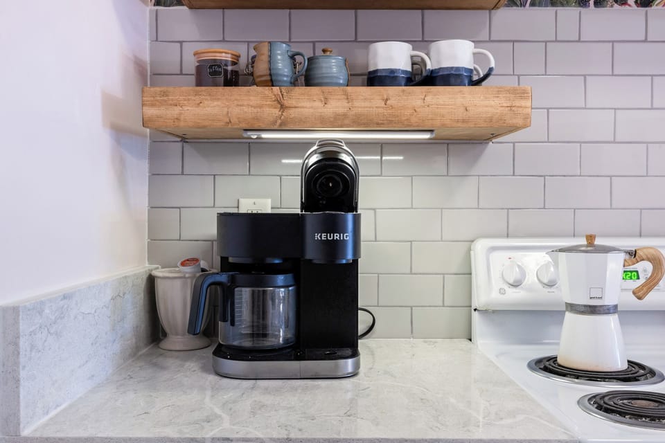 Cozy coffee bar with Keurig, mugs, and stylish shelving — perfect for your morning brew.