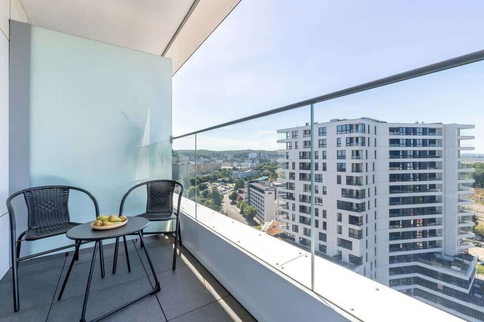  A balcony with outdoor furniture, including chairs and a small table, with a view of neighboring buildings.