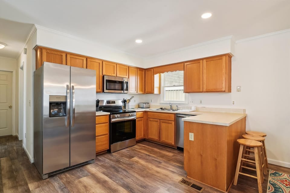 Your fully-equipped kitchen features warm wood cabinetry, stainless steel appliances, and a cozy breakfast bar—perfect for preparing home-cooked meals together.