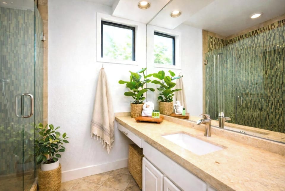  This tranquil master bath features a walk-in glass shower with custom mosaic tile and a serene, spa-like ambiance  