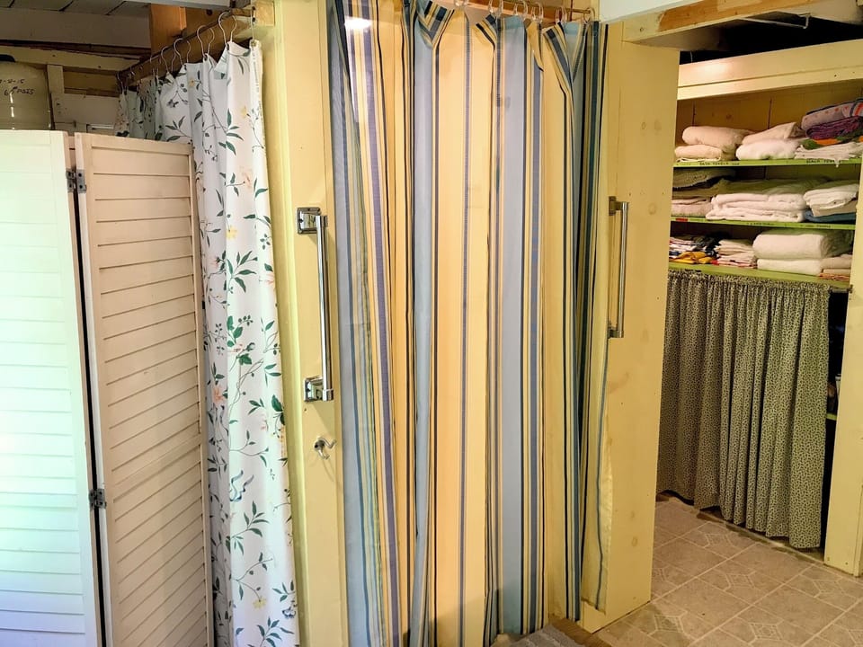 Hot water heater hidden behind screening. Shower curtains are closed, here.