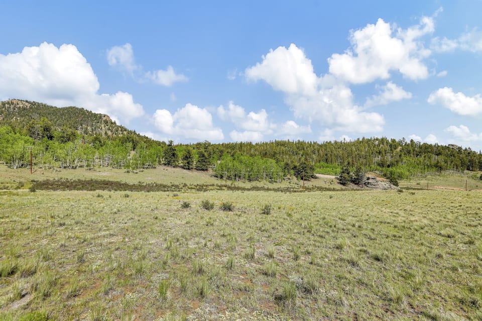 Expansive view of the open meadow and tree-covered hills surrounding the cabin.