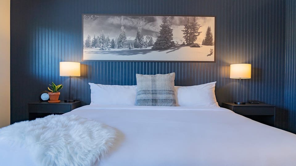 Unwind in plush linens beneath warm lamps and mountain art.