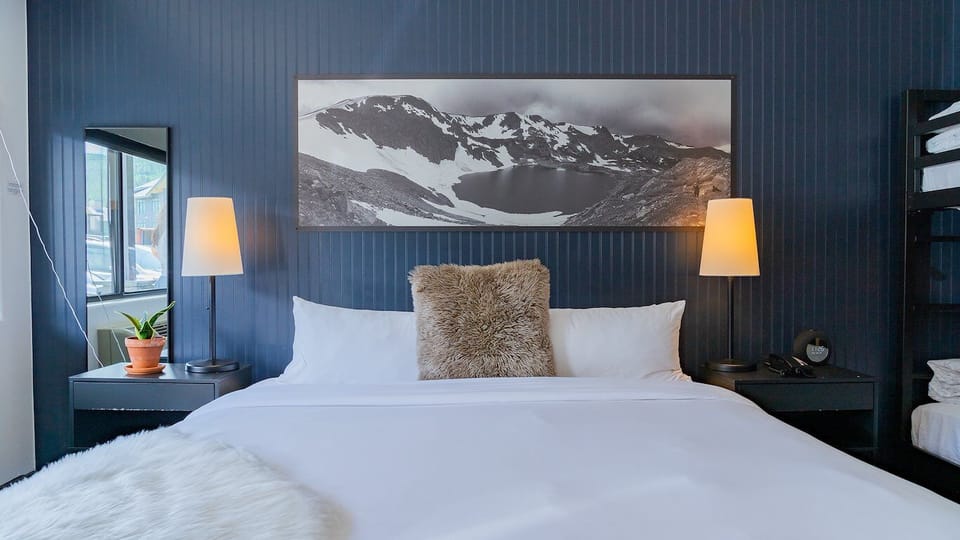 Unwind into crisp linens beneath calming alpine-inspired artwork.