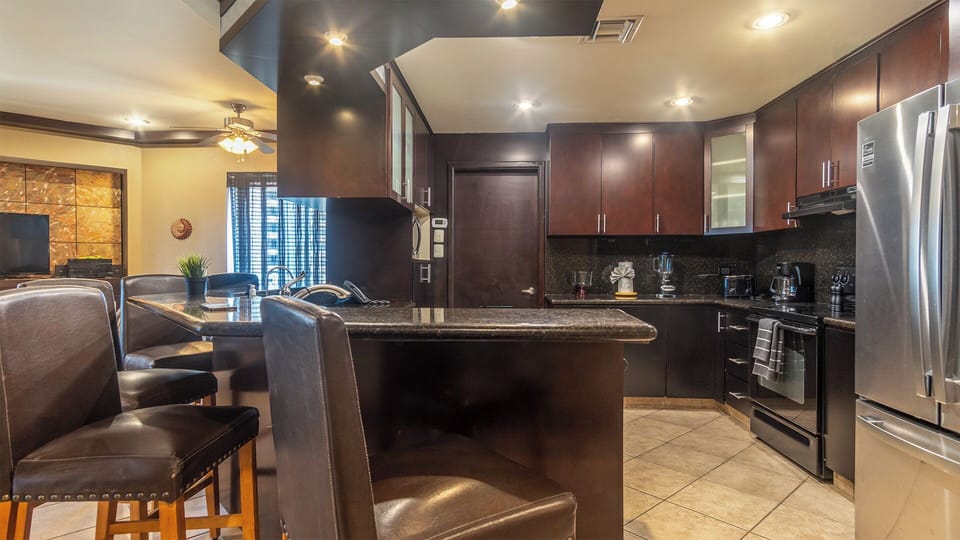 Dramatic with its dark granite and cabinets, the kitchen provides a spacious place to prepare meals.