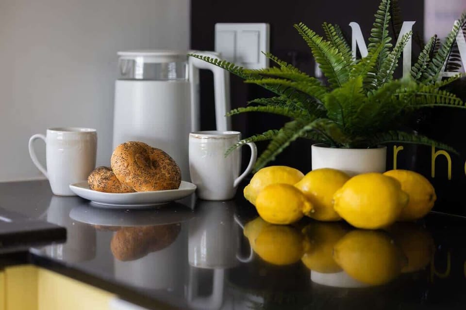 A small breakfast station with a coffee machine, croissants, lemons, and lush greenery.