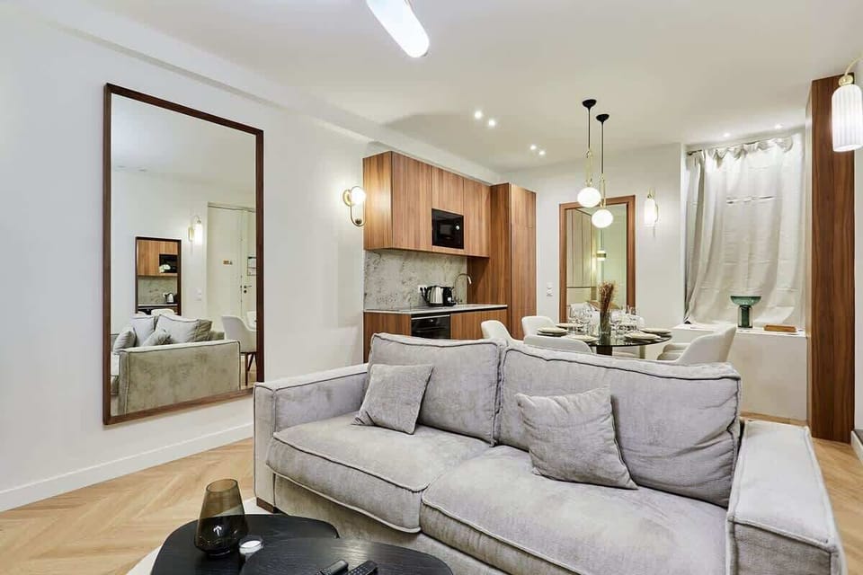 Belle pièce à vivre ouverte avec grand canapé lit, TV, table basse et coin repas lumineux.