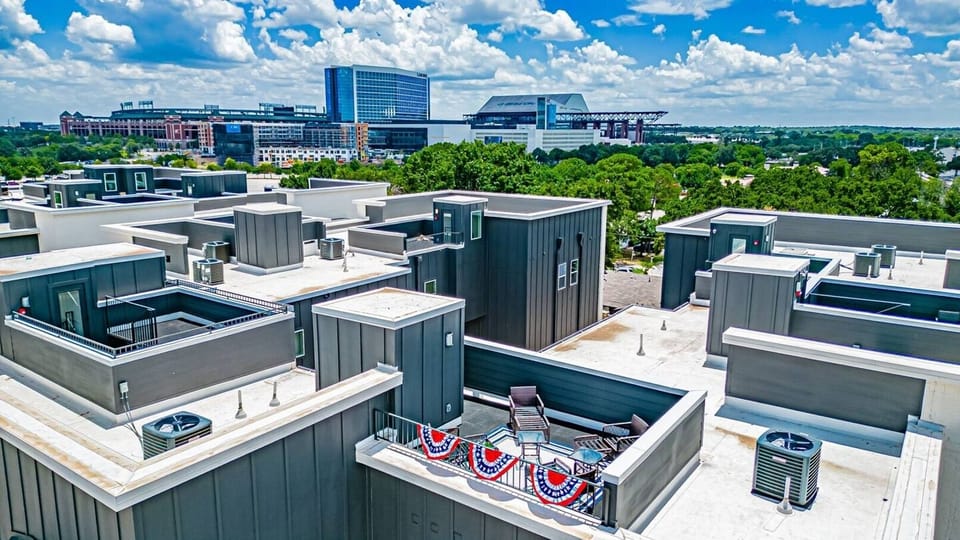 Experience the ultimate relaxation on a spacious rooftop deck with cozy lounge chairs and stunning views, perfect for sipping a drink as the sun sets over Arlington's entertainment district.