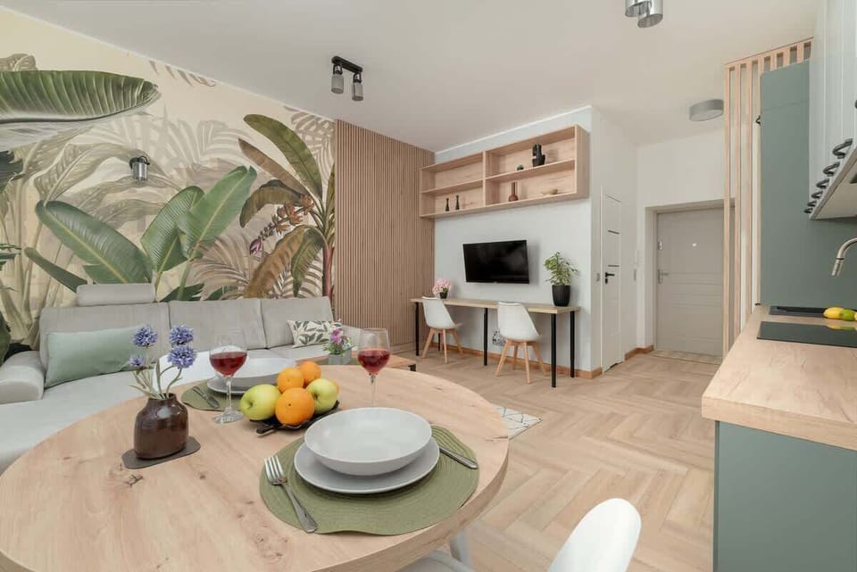 A dining area with elegant place settings and pastel-colored furniture, surrounded by tropical wall art and wood details.