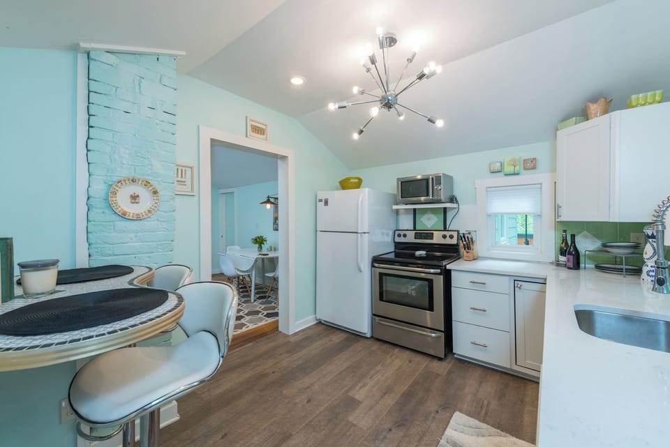 Bright, all-white kitchen complete with stainless appliances, ample countertop prep space, and a nearby dining area ideal for enjoying meals in comfort .